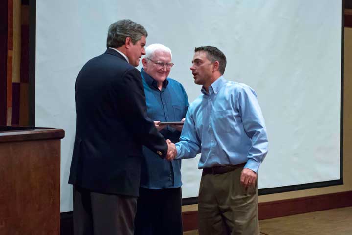 Attorney General  Mike Geraghty shaking hands with Assistant Attorney General Andrew Peterson.  Deputy Attorney General Rick Svobodny in background.