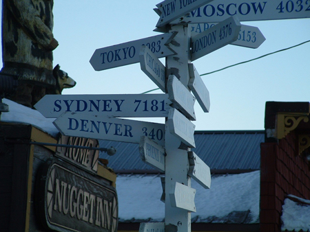 Mileage signs point in all directions showing distances to various large cities around the world