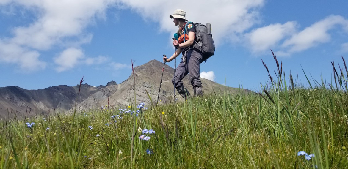 Laura Fox hiking up a mountain with wild flowers in the foreground